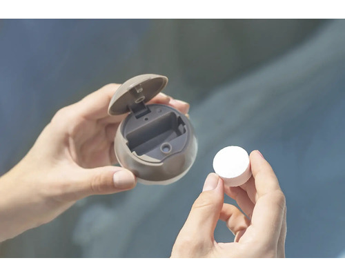 Les mains tiennent un distributeur rond avec un couvercle ouvert et un comprimé.