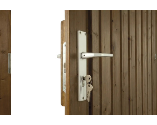 Holztür mit weißem Türdrücker, Langschild und steckendem Schlüssel.