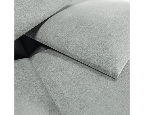 Gros plan d'un tissu d'ameublement gris à texture tissée avec des éléments de tissu qui se chevauchent.