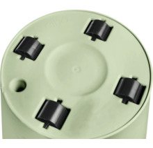Vue de dessous d'un pot de fleurs rond vert clair avec quatre roulettes en plastique noir et trou de drainage.