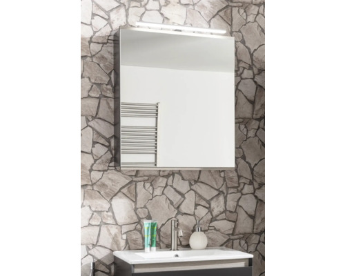 Salle de bains lumineuse avec armoire de toilette, éclairage LED, mur en pierre naturelle et lavabo avec robinet et accessoires.