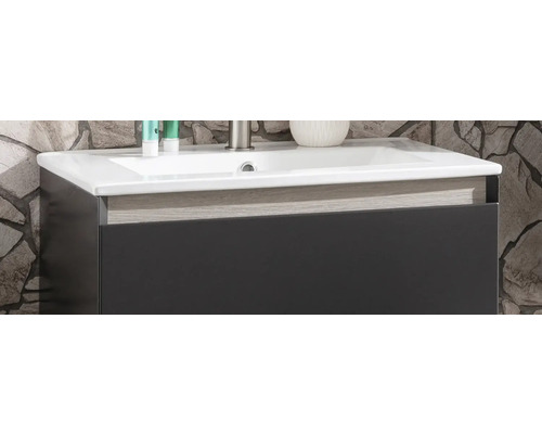 Waschtischunterschrank mit weißem Waschbecken, dunkler Front und Zierleiste in Holzoptik.