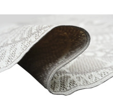 Gros plan d'un tapis à tissage plat avec motif géométrique montrant la structure du tissage et l'envers du coin replié.