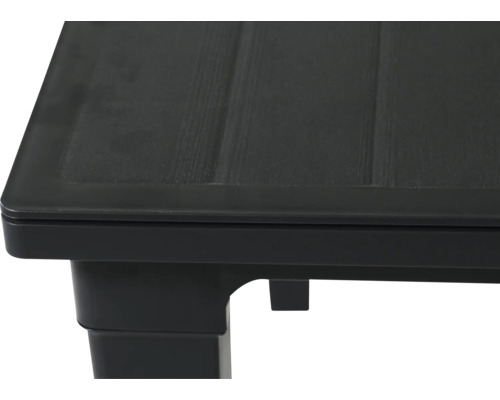 Vue rapprochée du coin d une table en plastique noir avec une surface texturée aspect bois.