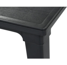Vue détaillée du coin d'une table en plastique noir avec une surface texturée.