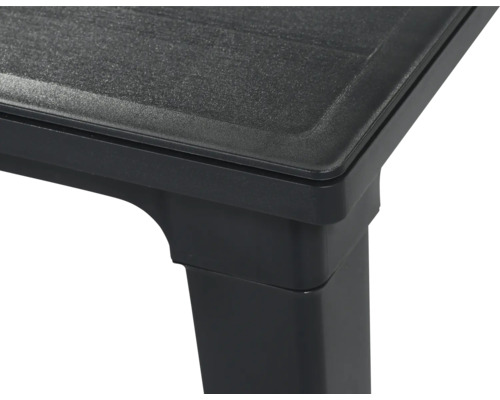 Vue détaillée du coin d'une table en plastique noir avec une surface texturée.
