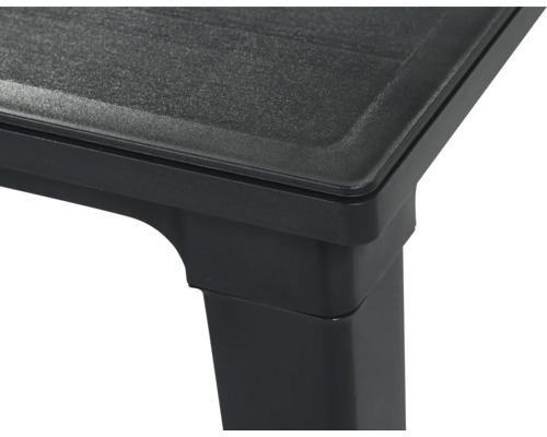 Gros plan d'un coin de table en plastique noir avec une surface texturée et un pied carré.
