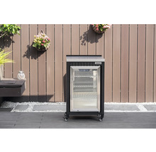 Réfrigérateur d extérieur Tenneker mobile avec porte vitrée et roulettes sur une terrasse devant une paroi en bois.