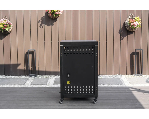 Meuble bas de cuisine d'extérieur mobile noir avec fentes d'aération et raccordement électrique sur une terrasse devant une clôture en bois.