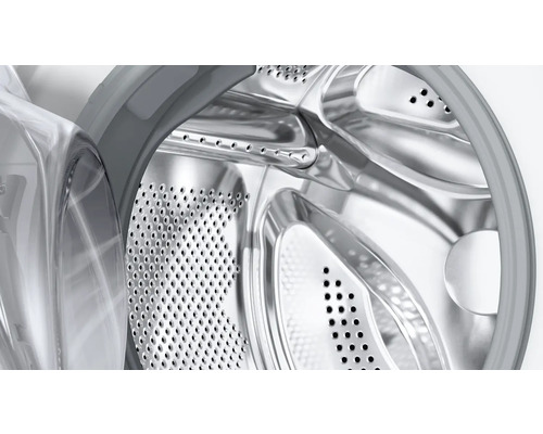 Gros plan d'un tambour de lave-linge en acier inoxydable avec perforations et vue à travers la porte ouverte.