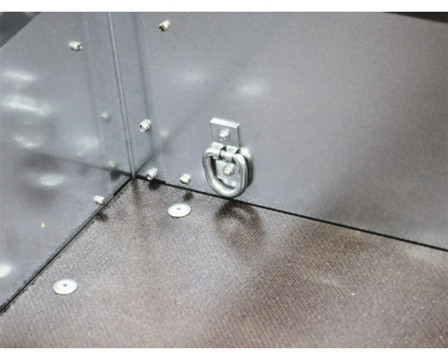 Anneau d'arrimage en métal monté sur la paroi latérale d'une remorque avec plancher structuré.