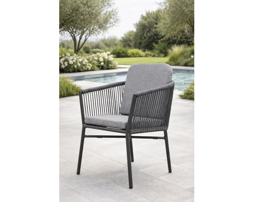 Fauteuil de jardin moderne avec structure en métal sombre, cordage gris et coussins gris sur une terrasse en pierre claire au bord d'une piscine.
