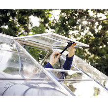 Eine Person stellt den manuellen Fensteraufsteller an einem Gewächshaus aus Aluminium und Glas ein.