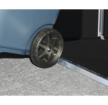 Nahaufnahme eines Rades beim Überfahren einer flachen Metallschwelle an einem Gartenhaus oder einer Aufbewahrungsbox.