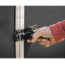 Hand bedient einen schwarzen Riegelverschluss an einem Gerätehaus.