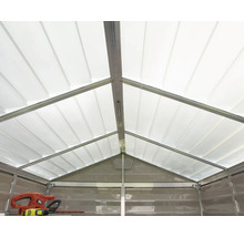 Vue intérieure d'un abri de jardin avec un toit à deux versants translucide et un cadre métallique. Un taille-haie est posé sur une étagère.