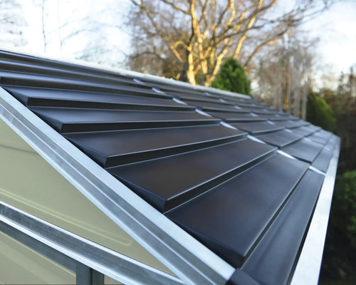 Gros plan d'un toit à deux versants d'un abri de jardin en métal avec des panneaux gris foncé et des profilés en aluminium argenté.