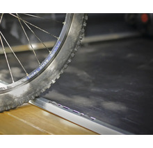 Pneu de vélo sur un rail de chargement ou un profilé de transition en métal.