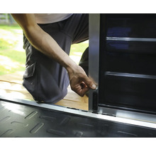 Personne installant un verrou sur une armoire de rangement en métal avec un cadre argenté et des panneaux noirs.