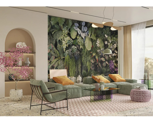 Salon moderne avec un grand papier peint tropical, canapé modulaire vert, fauteuil, table en verre et décoration botanique.