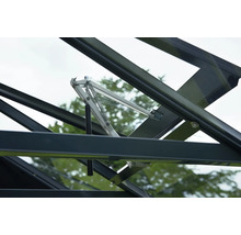Automatischer Fensteröffner aus Metall für Gewächshäuser mit Federmechanismus montiert an einem schwarzen Dachfenster.