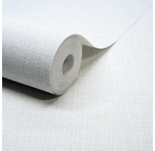 Papier peint intissé gris clair avec une fine structure en lin, un rouleau de papier peint partiellement déroulé.