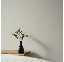 Papier peint intissé avec structure en lin fine dans une pièce minimaliste avec table en bois et vase.