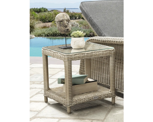 Table d appoint carree en polyrotin avec plateau en verre et etagere sur une terrasse lumineuse au bord de la piscine pres d une chaise longue.