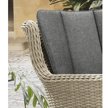 Détail d'un fauteuil de jardin en polyrotin tressé beige avec un coussin gris.