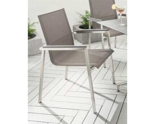Chaise de jardin moderne en acier inoxydable avec textile sur une terrasse lumineuse avec table et plantes.