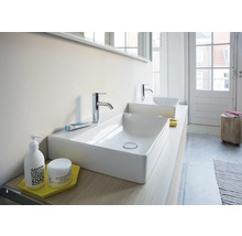 Modernes Badezimmer mit zwei rechteckigen Aufsatzwaschbecken aus weißer Keramik und verchromten Armaturen auf einer hellen Waschtischplatte.