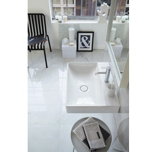 Modernes helles Badezimmer mit weißem rechteckigem Waschtisch, verchromter Armatur, großen Fliesen in Marmoroptik und schwarz-weißer Dekoration.