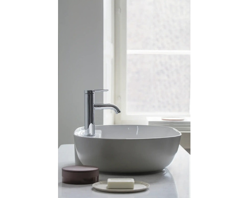 Moderne Chrom-Badarmatur auf einem weißen Aufsatzwaschbecken aus Keramik in einem hellen Badezimmer.