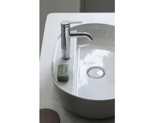 Moderner weißer Aufsatzwaschtisch mit verchromter Einhebel-Waschtischarmatur und einem Stück Seife auf der Ablage.