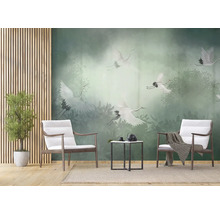 Papier peint panoramique avec des grues blanches au-dessus d'une forêt de brume verte dans un salon moderne avec fauteuils en bois.