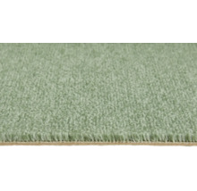 Gros plan d'une moquette verte douce à poils denses avec envers visible.