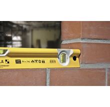 Niveau à bulle jaune Stabila R 300 utilisé pour l'alignement d'un mur de briques.