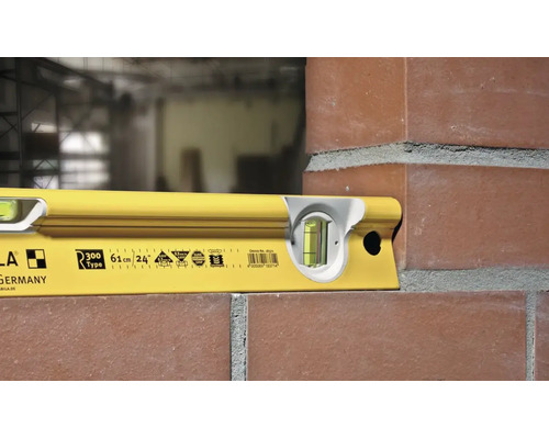 Niveau à bulle jaune Stabila R 300 utilisé pour l'alignement d'un mur de briques.