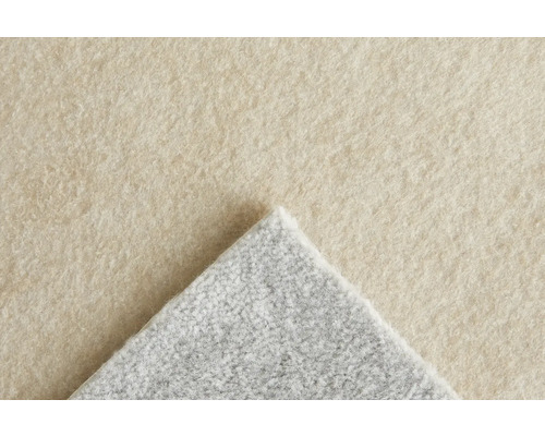 Gros plan sur un tapis avec une surface beige et un envers gris.