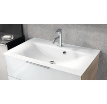 Lavabo moderne en verre blanc avec mitigeur monocommande chromé sur un meuble sous-vasque blanc dans une salle de bains.