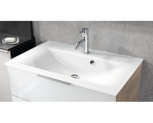 Lavabo moderne en verre blanc avec mitigeur monocommande chromé sur un meuble sous-vasque blanc dans une salle de bains.