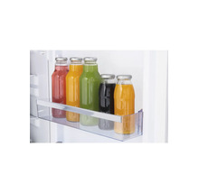 Bouteilles en verre avec des liquides colorés dans un balconnet de porte de réfrigérateur transparent.