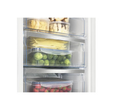 Congélateur avec aliments organisés de manière claire dans des tiroirs transparents tels que choux de Bruxelles et fraises.