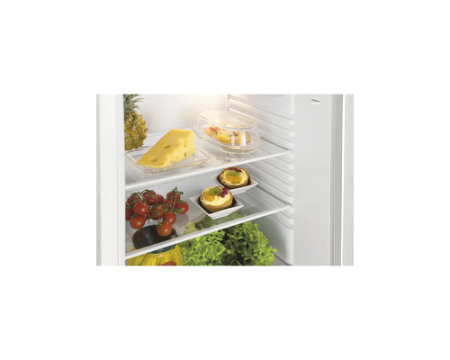 Réfrigérateur ouvert avec clayettes en verre, rempli d'aliments frais comme du fromage, des tomates, des tartelettes aux fruits et de la salade.
