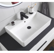 Vasque à poser rectangulaire en céramique blanche avec un robinet noir sur un plan de toilette sombre dans une salle de bains.