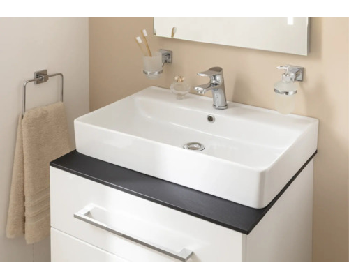 Vasque à poser blanche sur un meuble sous-vasque avec plan de travail foncé, robinetterie chromée et accessoires de salle de bain.