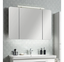 Armoire de toilette à trois portes avec coins arrondis et éclairage LED au-dessus d'un lavabo blanc dans une salle de bains lumineuse.