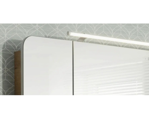 Armoire de toilette avec éclairage LED et angles arrondis devant un mur tapissé.