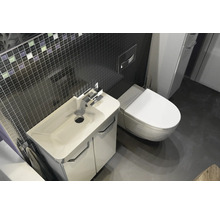 Salle de bain moderne avec meuble sous-lavabo blanc, lavabo en céramique, WC suspendu et mur en mosaïque sombre.