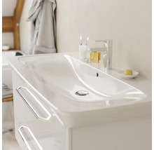 Meuble sous-vasque blanc moderne avec deux tiroirs, poignées argentées et lavabo en céramique intégré dans une salle de bains lumineuse.